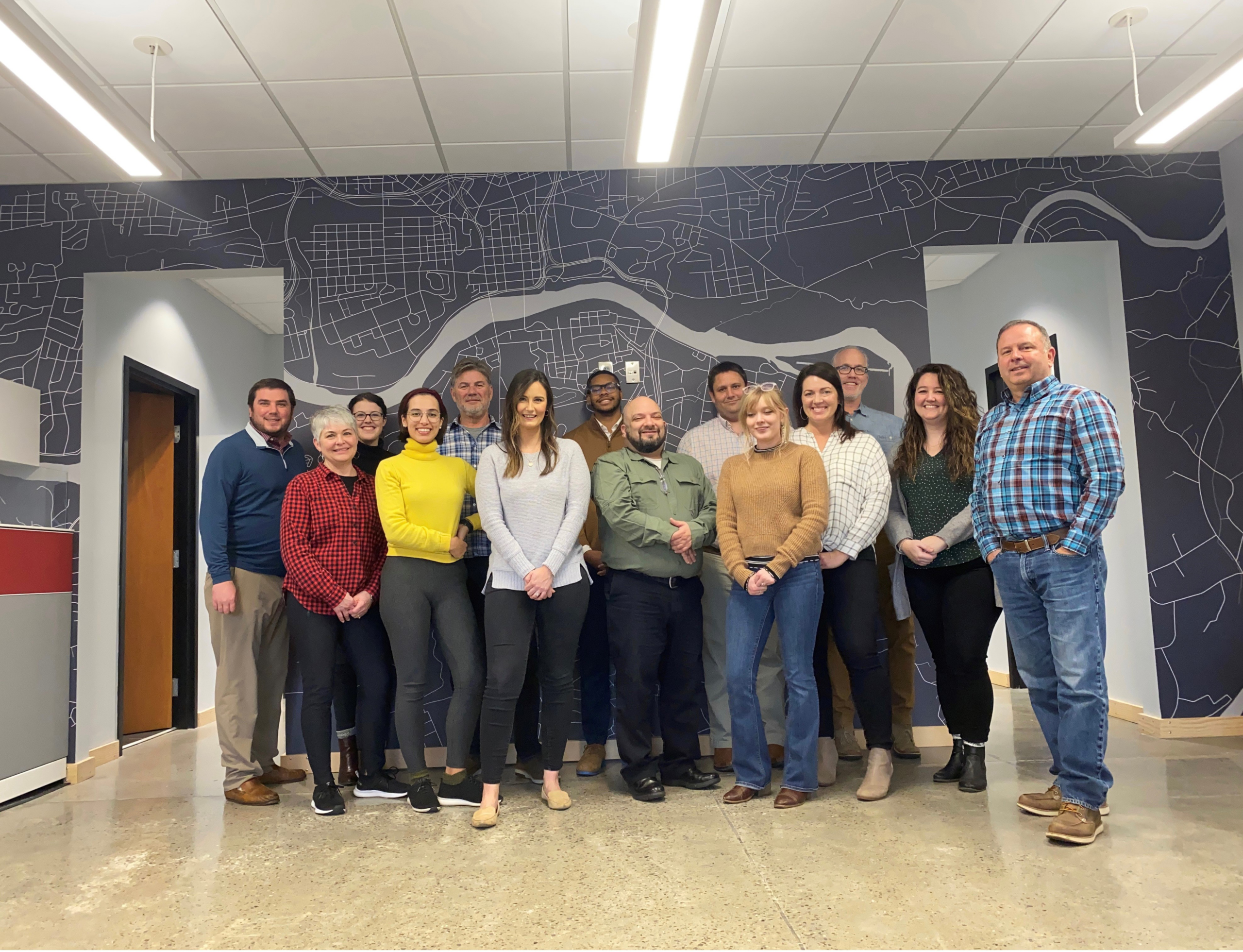 Group photo of GAE Architecture + Design team members in a modern office setting, showcasing a collaborative company culture.