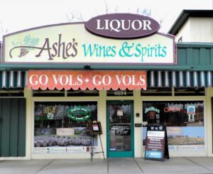 Ashe's Wines & Spirits storefront featuring "LIQUOR" sign, "GO VOLS" banners, and inviting entrance, designed and built by George Ewart, a top commercial architect firm in Knoxville, TN.