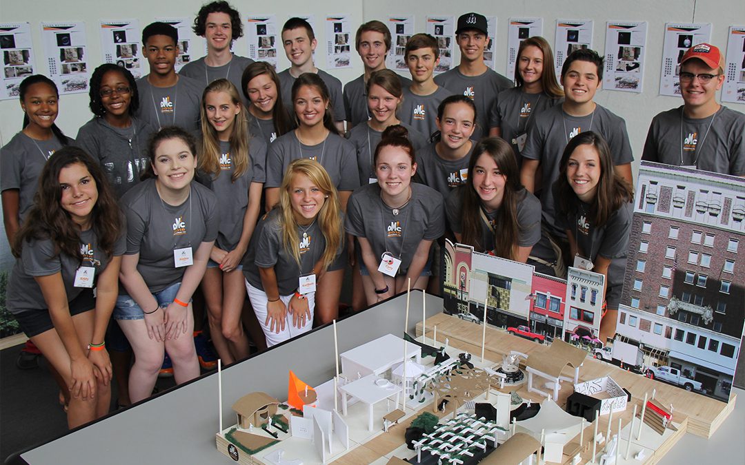 Group of high school students participating in the University of Tennessee's Summer Design Camp, showcasing architectural models and designs, wearing matching grey camp t-shirts, with a focus on mentorship and hands-on learning in architecture.