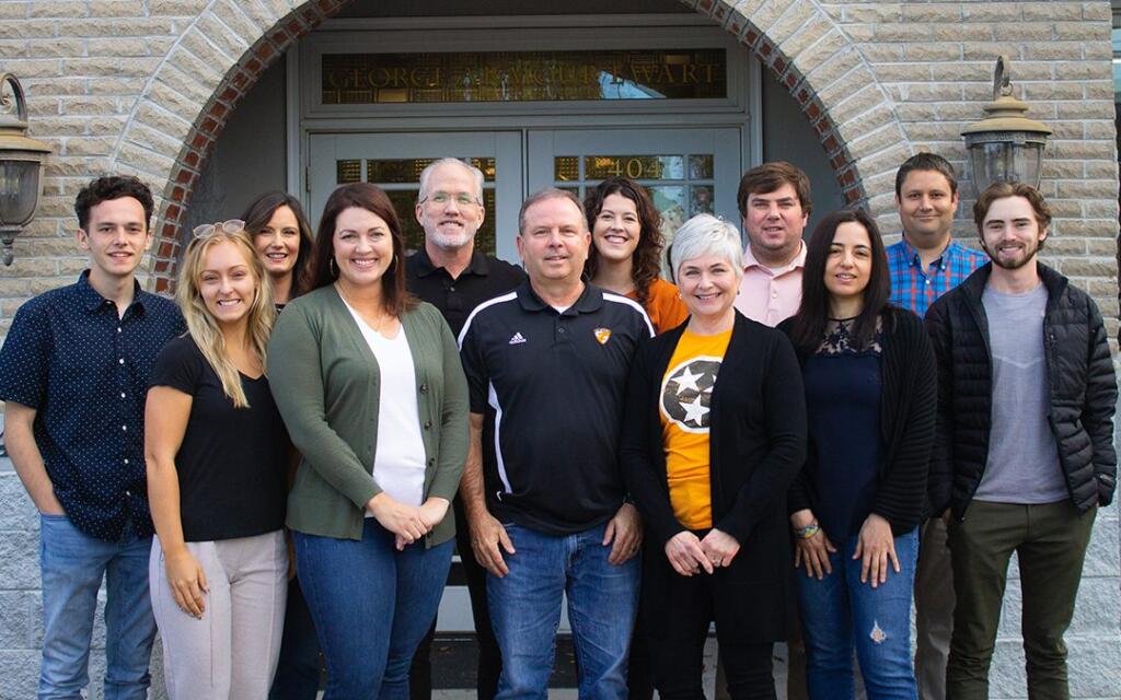 Group photo of GAE Architecture + Design team members outside their Knoxville, TN office, showcasing a diverse team of commercial architects engaged in architecture and design culture.