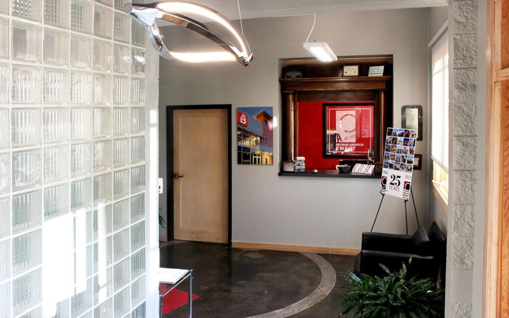 Interior of GAE Architecture + Design office featuring glass block wall, modern lighting, and a reception area with architectural displays and promotional materials, emphasizing the firm's focus on innovative design in Knoxville, TN.