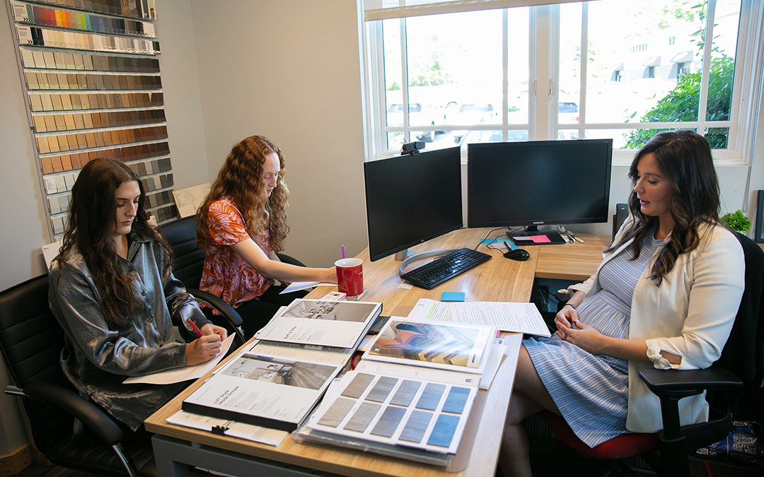 Interior designers collaborating at a desk with color swatches and project materials, showcasing a creative workspace at GAE Architecture + Design, a top commercial architect firm in Knoxville, TN.