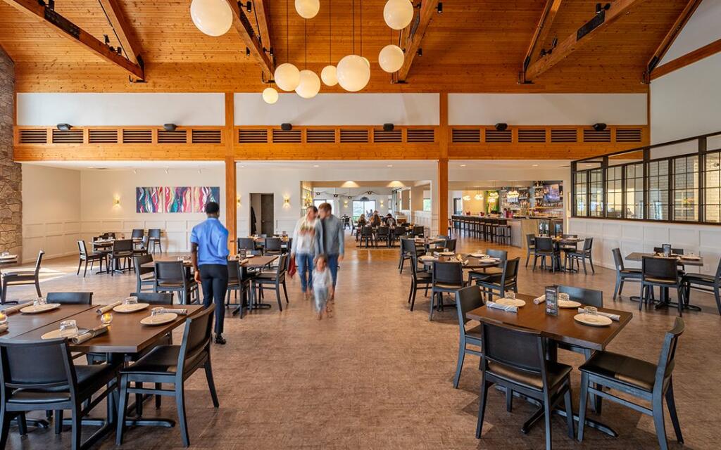 Modern restaurant interior featuring wooden beams, round pendant lights, and tables set for dining, illustrating hospitality design by GAE Architecture + Design, a top commercial architect firm in Knoxville, TN.