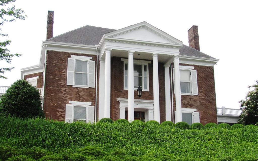 Knollwood Mansion, a classic architectural design featuring brick façade, white columns, and manicured hedges, designed and built by George Ewart, a top commercial architect firm in Knoxville, TN.