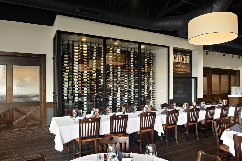 Interior view of Gaucho Urbano restaurant in Pigeon Forge, showcasing a wine wall and dining setup with white tablecloths, emphasizing a welcoming atmosphere and Brazilian steakhouse concept, designed and built by George Ewart, a top commercial architect firm in Knoxville, TN.