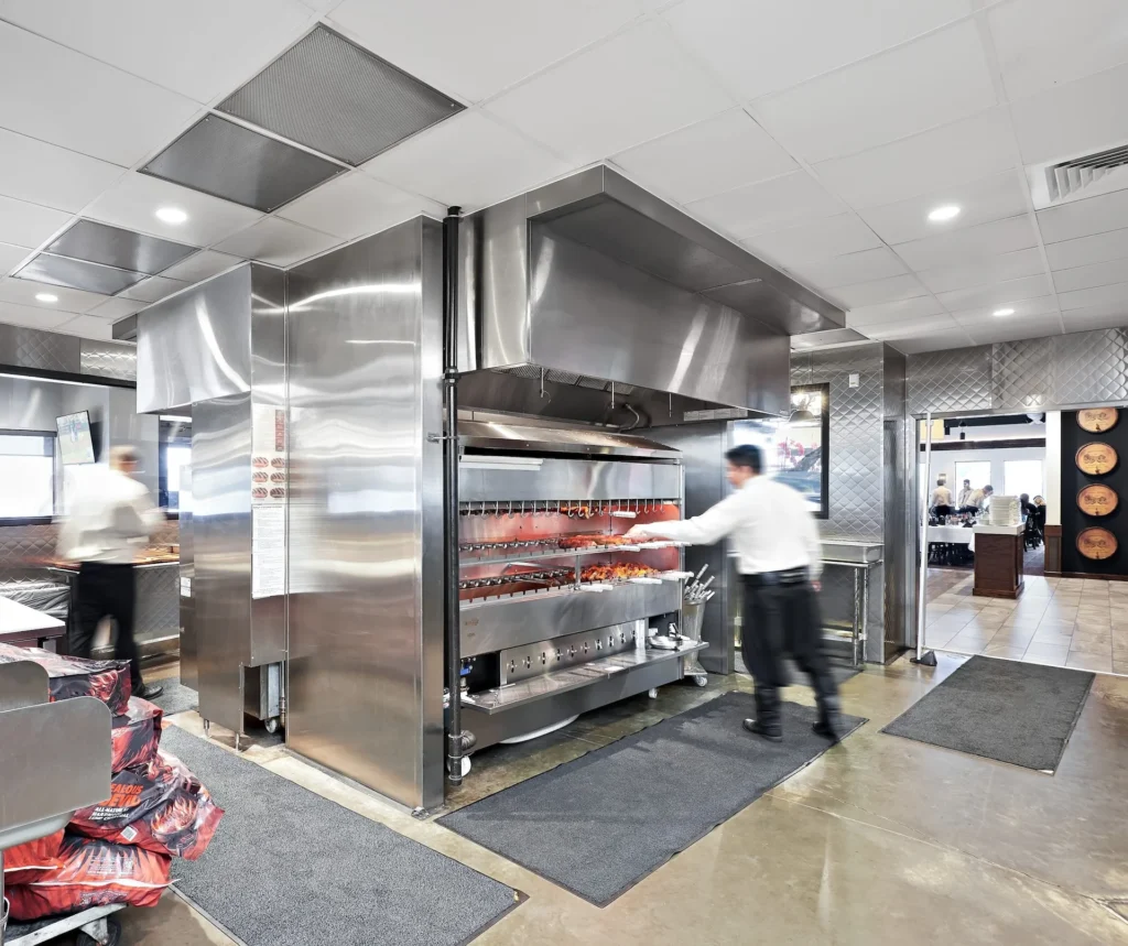 Chef preparing meats in a stainless steel grill at Gaucho Urbano restaurant, showcasing Brazilian grilling culture in Pigeon Forge, Tennessee, designed and built by George Ewart, a top commercial architect firm in Knoxville, TN.