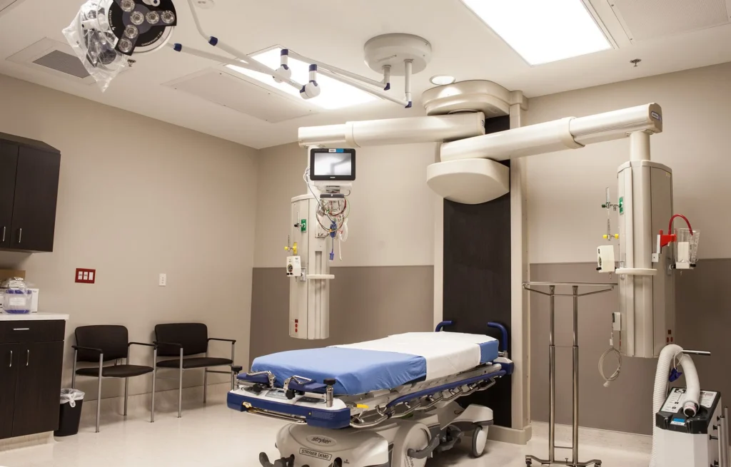 Medical examination room featuring advanced imaging equipment, patient bed, and clinical supplies, designed for efficient healthcare delivery at CHRISTUS Health Medical Center, Port Arthur, Texas, designed and built by George Ewart, a top commercial architect firm in Knoxville, TN.