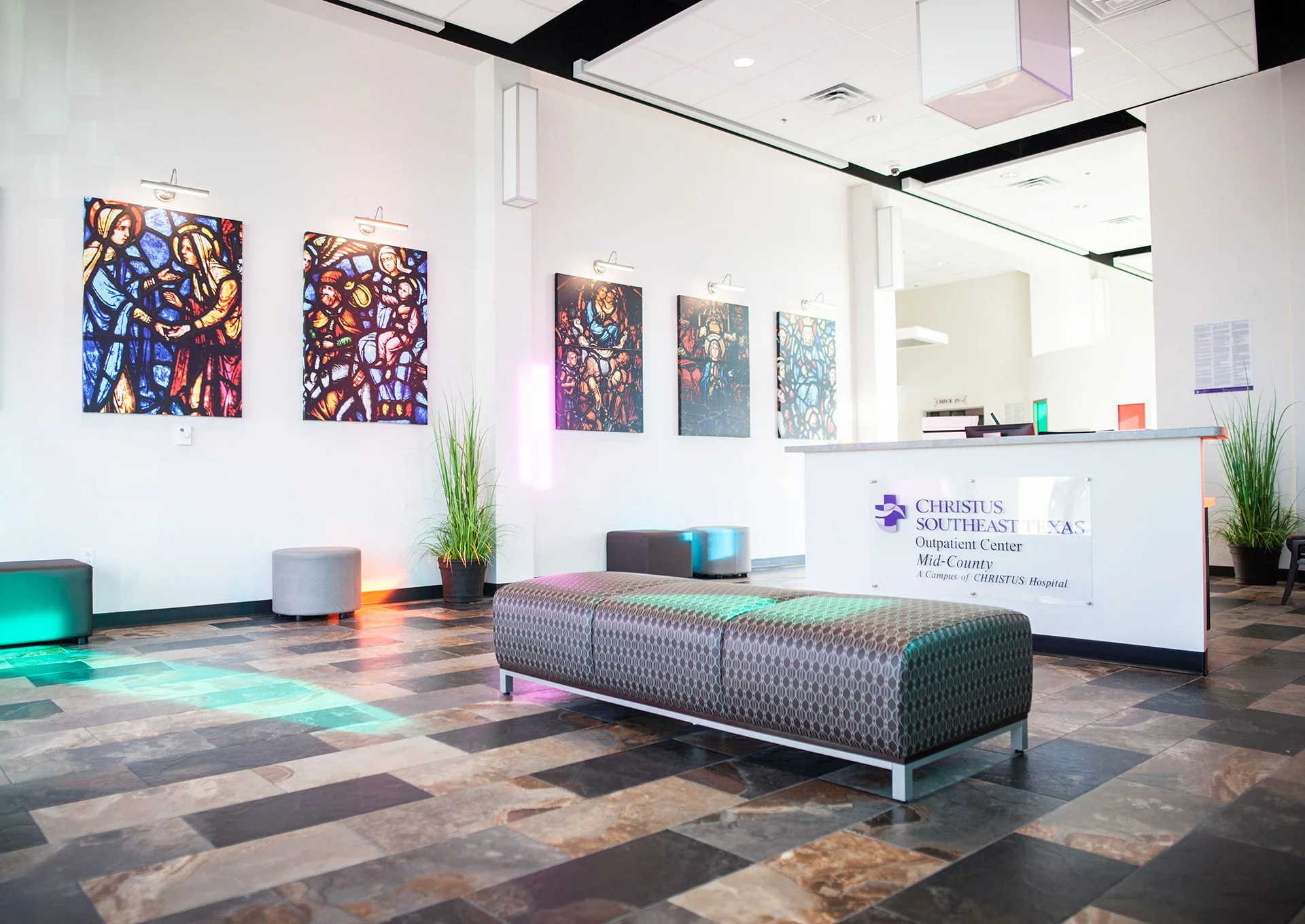 Interior of CHRISTUS Southeast Texas Outpatient Center Mid-County, featuring stained glass artwork, modern seating, and a reception desk, designed and built by George Ewart, a top commercial architect firm in Knoxville, TN.