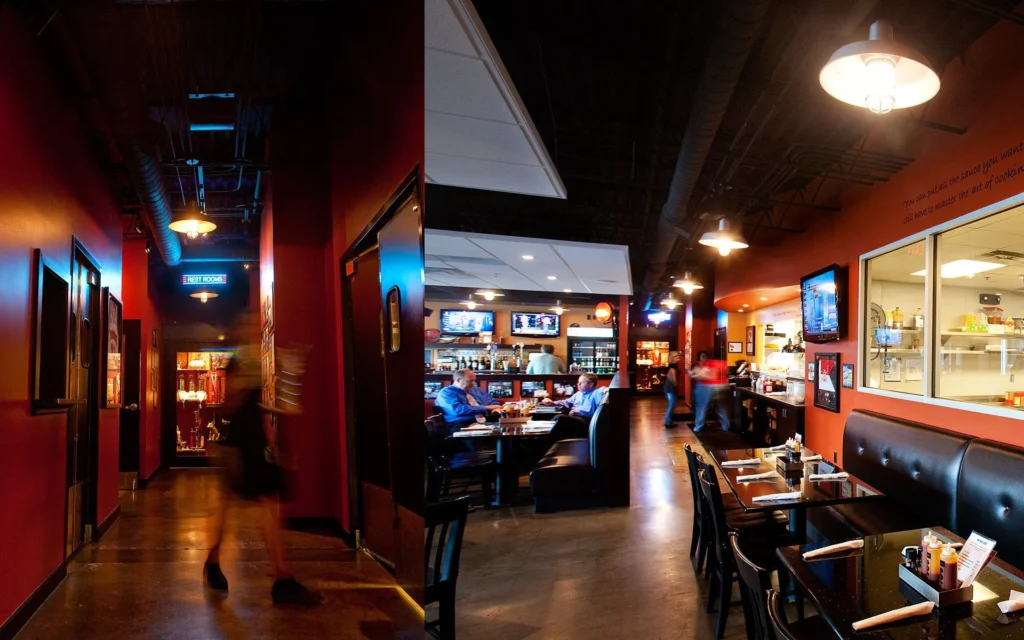 Interior view of Dead End BBQ restaurant in Knoxville, TN, showcasing a dining area with booths, a visible cook line, and a corridor leading to restrooms, designed to enhance community gathering and transparency in food preparation, reflecting the architectural vision by GAE Architecture + Design.