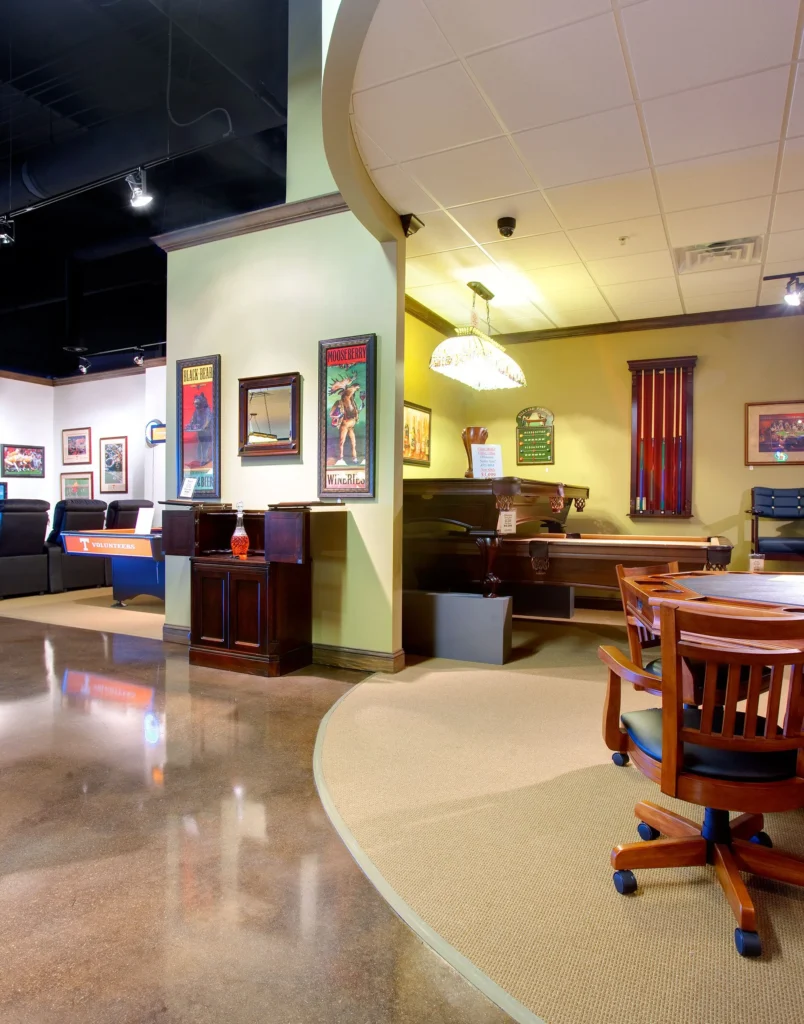 Interior view of a showroom designed by GAE Architecture + Design, featuring pool tables, residential-style vignettes, and decorative wall art, enhancing the customer experience in home entertainment. Designed and built by George Ewart, a top commercial architect firm in Knoxville, TN.