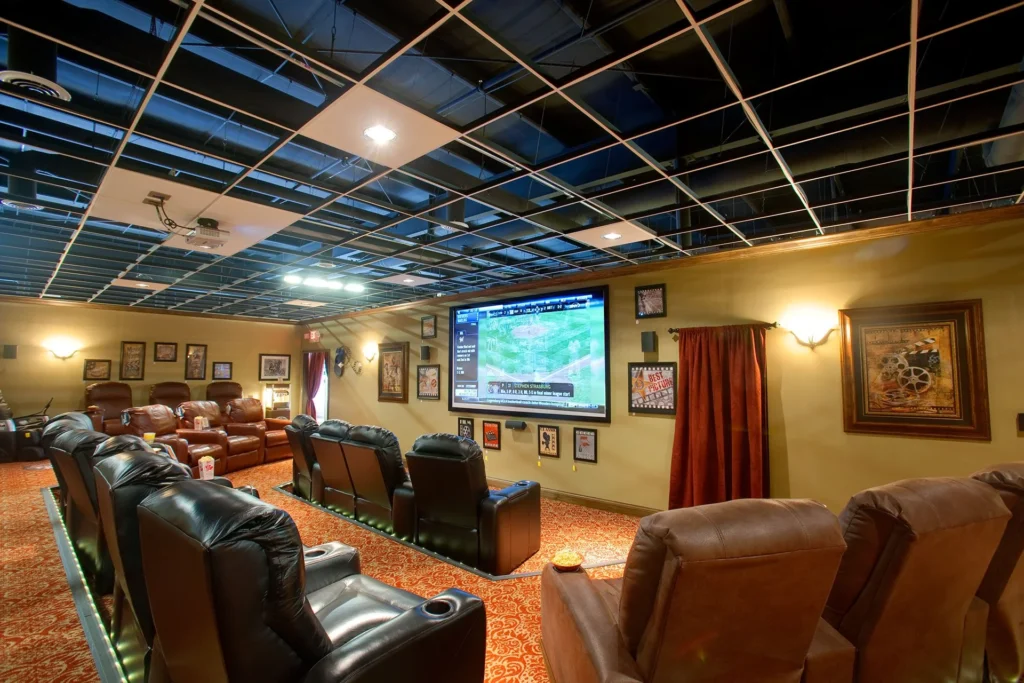 Home movie theater featuring plush seating, a large projection screen, and decorative wall art, designed and built by George Ewart, a top commercial architect firm in Knoxville, TN.