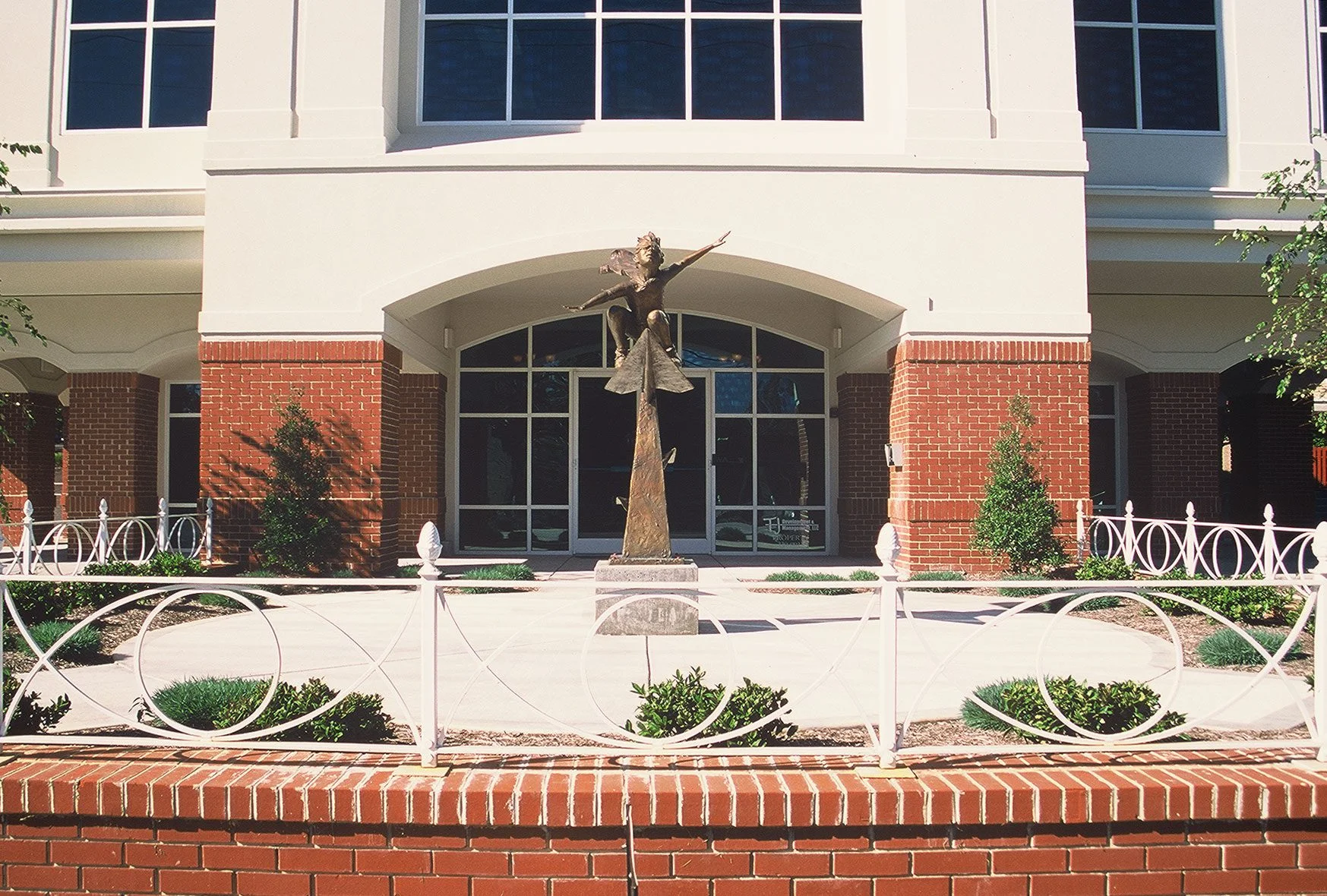 Meridian Office Building entrance with a bronze sculpture, custom wrought-iron railings, and landscaped plaza, showcasing the renovation designed and built by George Ewart, a top commercial architect firm in Knoxville, TN.