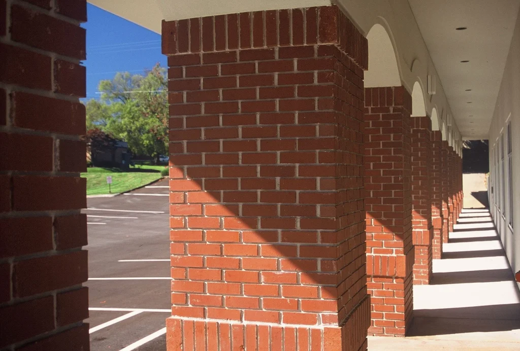 Brick columns supporting a covered walkway in a commercial building, highlighting architectural design elements and the surrounding parking area, designed and built by George Ewart, a top commercial architect firm in Knoxville, TN.