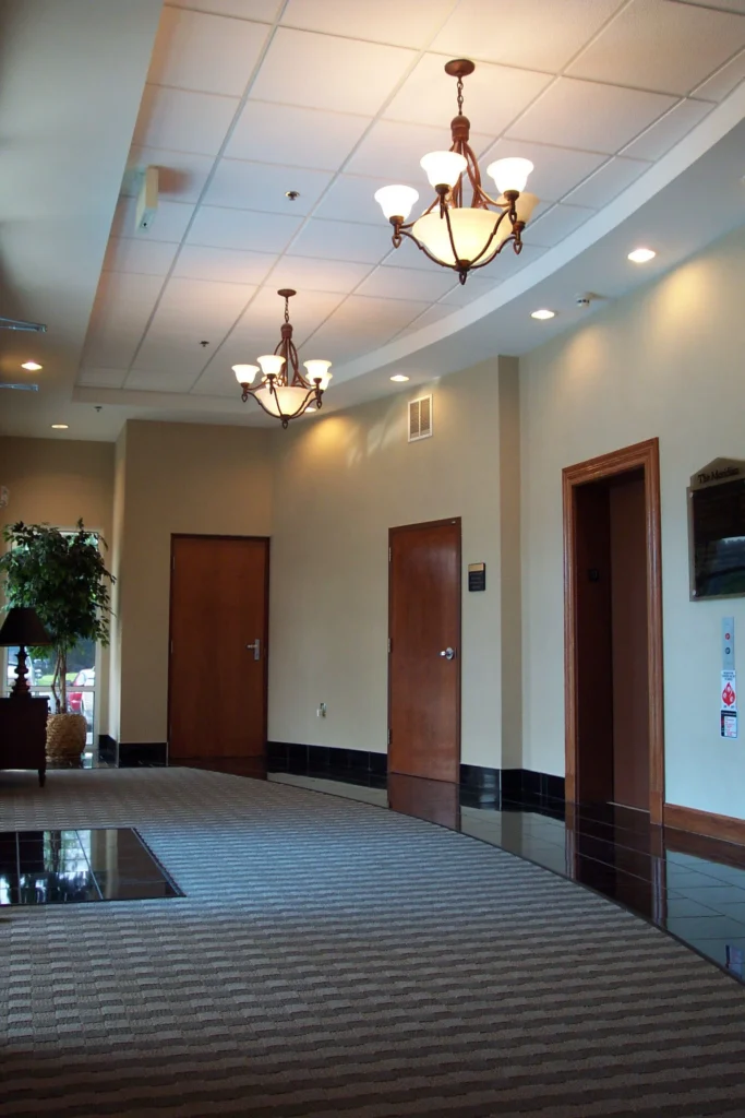 Interior view of the Meridian Building renovation featuring elegant chandeliers, polished flooring, and wooden doors, designed and built by George Ewart, a top commercial architect firm in Knoxville, TN.