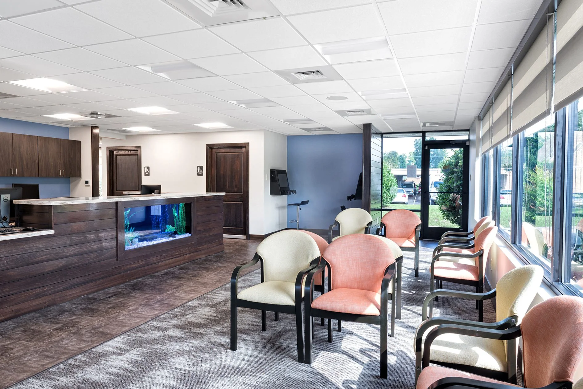 Interior of Myers Orthodontics featuring a modern reception area with a welcoming design, including a wooden reception desk with an aquarium, comfortable seating in various colors, and large windows for natural light, designed and built by George Ewart, a top commercial architect firm in Knoxville, TN.