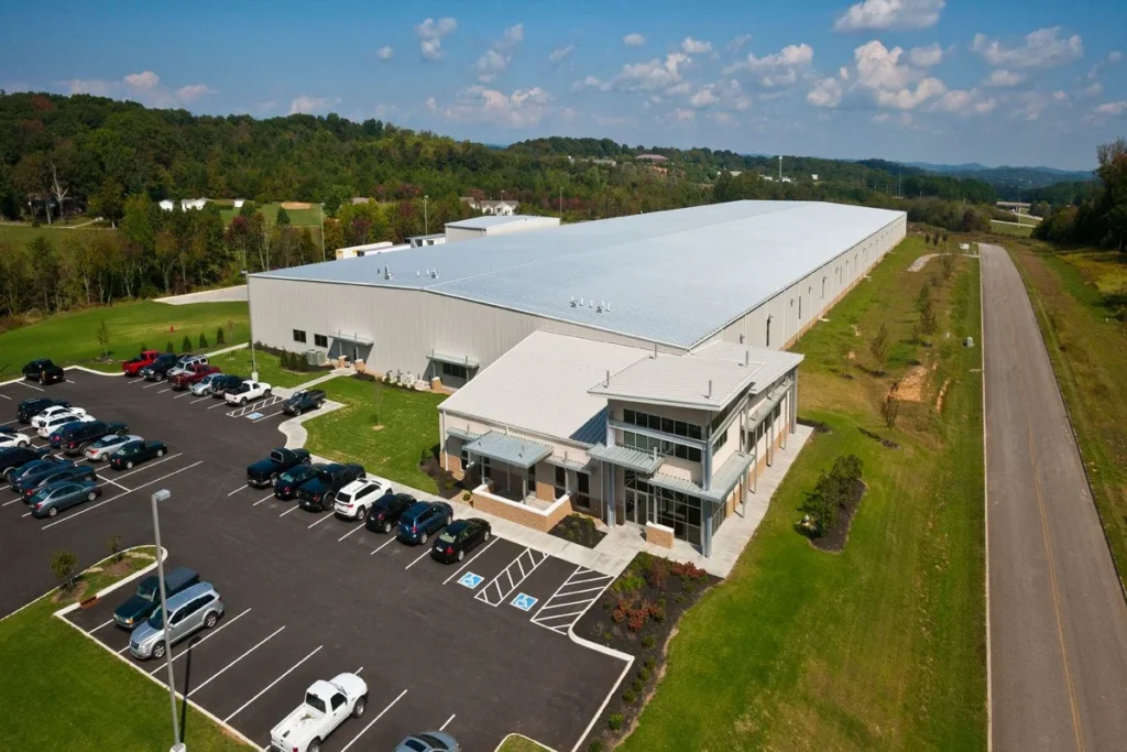 Aerial view of a large industrial building with a modern facade, surrounded by a spacious parking lot filled with vehicles, showcasing GAE Architecture + Design's commercial project in Knoxville, TN.