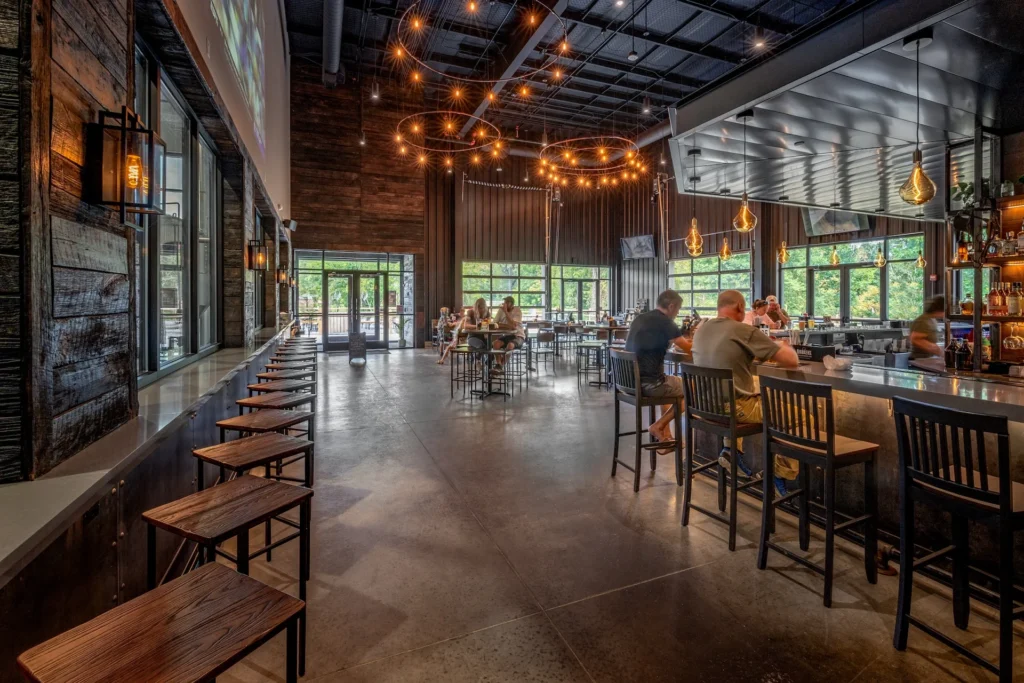 Interior view of Iron Forge Brewing Co. showcasing a spacious taproom with a modern bar, wooden seating, and large windows, designed and built by George Ewart, a top commercial architect firm in Knoxville, TN.