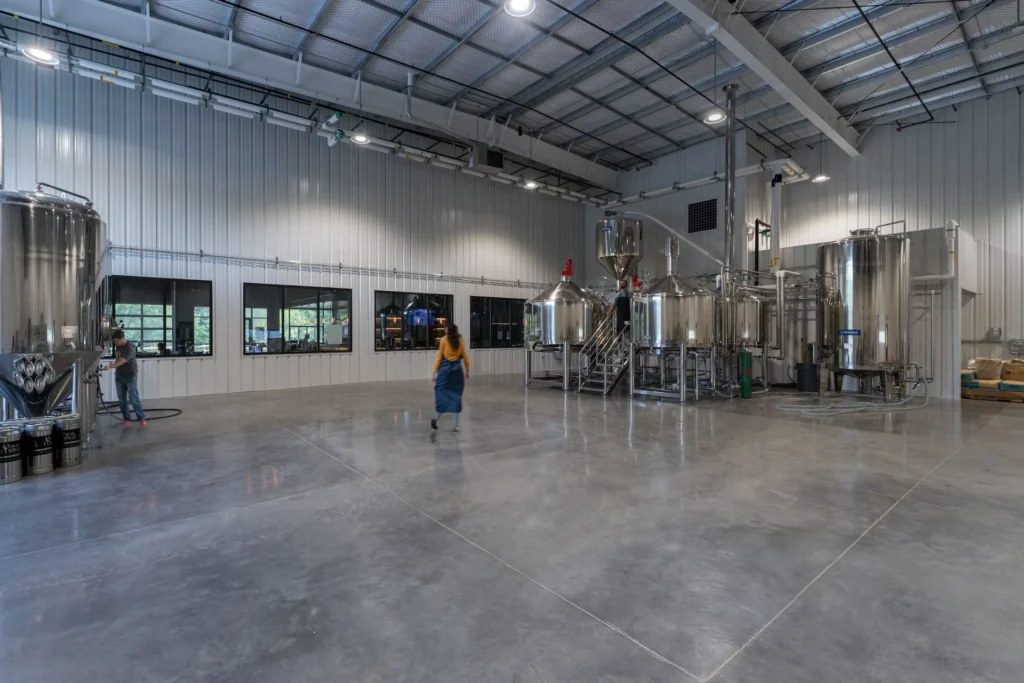 Interior of Iron Forge Brewing Co. showcasing stainless steel fermenters and brewing equipment, designed for visibility and efficiency, highlighting the brewery's operational and hospitality focus, designed and built by George Ewart, a top commercial architect firm in Knoxville, TN.