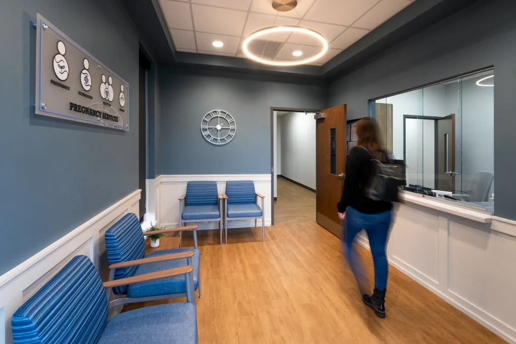 Interior view of the renovated Pregnancy Center at Catholic Charities, featuring blue accent walls, modern seating, and a welcoming atmosphere, designed and built by George Ewart, a top commercial architect firm in Knoxville, TN.
