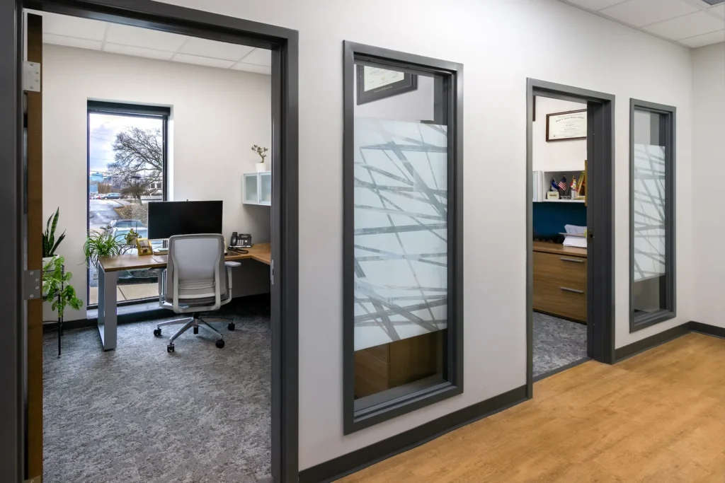 Interior view of renovated office space at Catholic Charities of East Tennessee, featuring modern workstations, large windows for natural light, and warm wood accents, designed and built by George Ewart, a top commercial architect firm in Knoxville, TN.