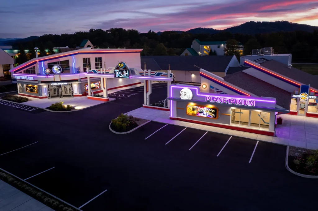 Futuristic attraction exterior featuring "Truth" and "Planetarium" signage, illuminated by colorful lights, designed for immersive experiences in Pigeon Forge, Tennessee, showcasing architectural innovation by George Ewart, a top commercial architect firm in Knoxville, TN.