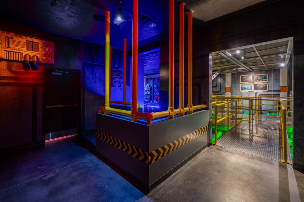 Futuristic interior design of the Truth Traveler attraction in Pigeon Forge, featuring colorful pipes, immersive lighting, and industrial elements, designed and built by George Ewart, a top commercial architect firm in Knoxville, TN.