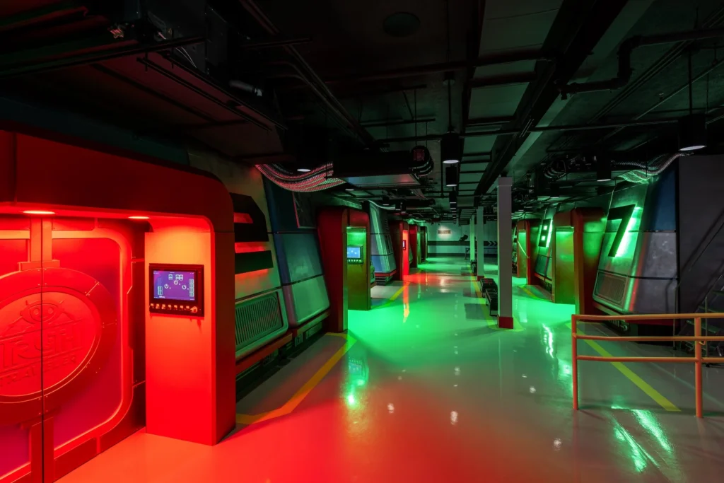 Futuristic interior of the Truth Traveler attraction featuring illuminated red and green walls, interactive screens, and sleek design elements, designed and built by George Ewart, a top commercial architect firm in Knoxville, TN.
