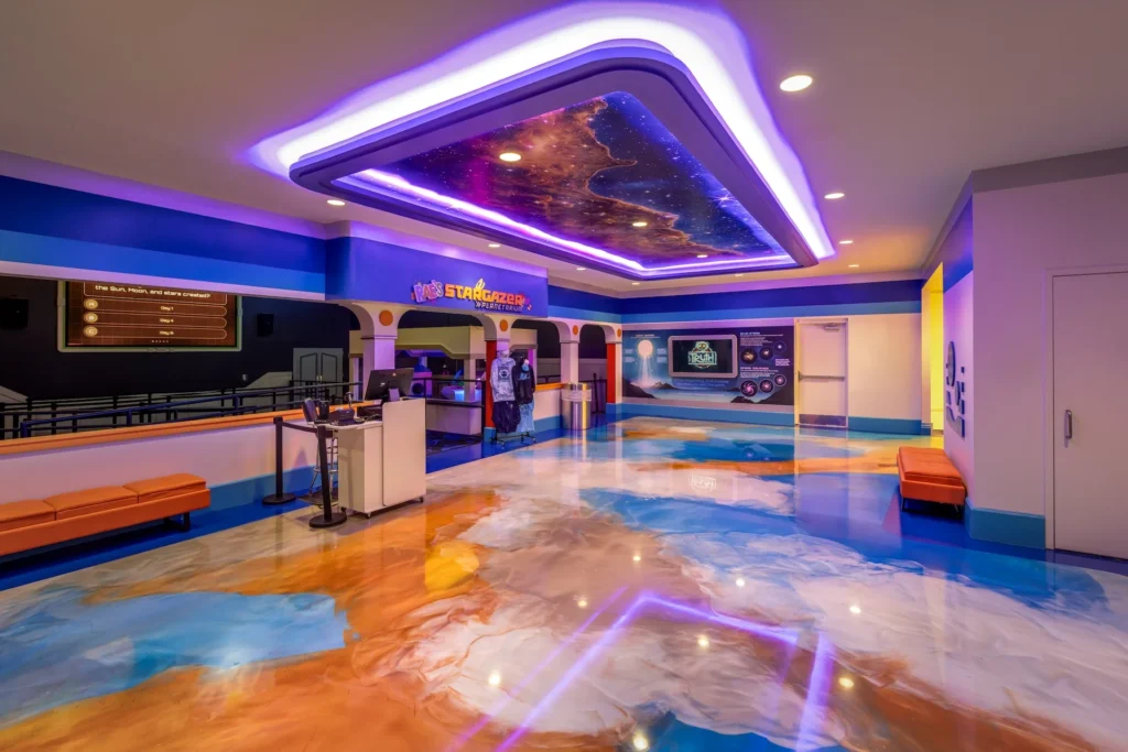 Lobby of Rae’s Stargazer Planetarium featuring vibrant blue and orange flooring, illuminated ceiling with galaxy design, and interactive display areas, designed and built by George Ewart, a top commercial architect firm in Knoxville, TN.