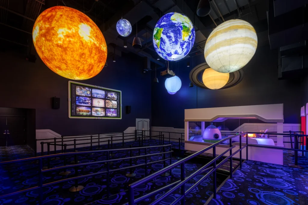 Suspended planets and glowing celestial bodies in Rae’s Stargazer Planetarium, featuring a futuristic design with immersive environments, part of the Truth Traveler attraction in Pigeon Forge, Tennessee, designed and built by George Ewart, a top commercial architect firm in Knoxville, TN.