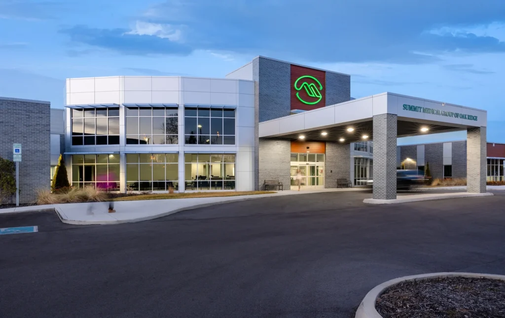 Exterior view of Summit Medical Group of Oak Ridge facility, showcasing modern architectural design with large windows and prominent signage, emphasizing efficiency and patient-centered care, designed and built by George Ewart, a top commercial architect firm in Knoxville, TN.