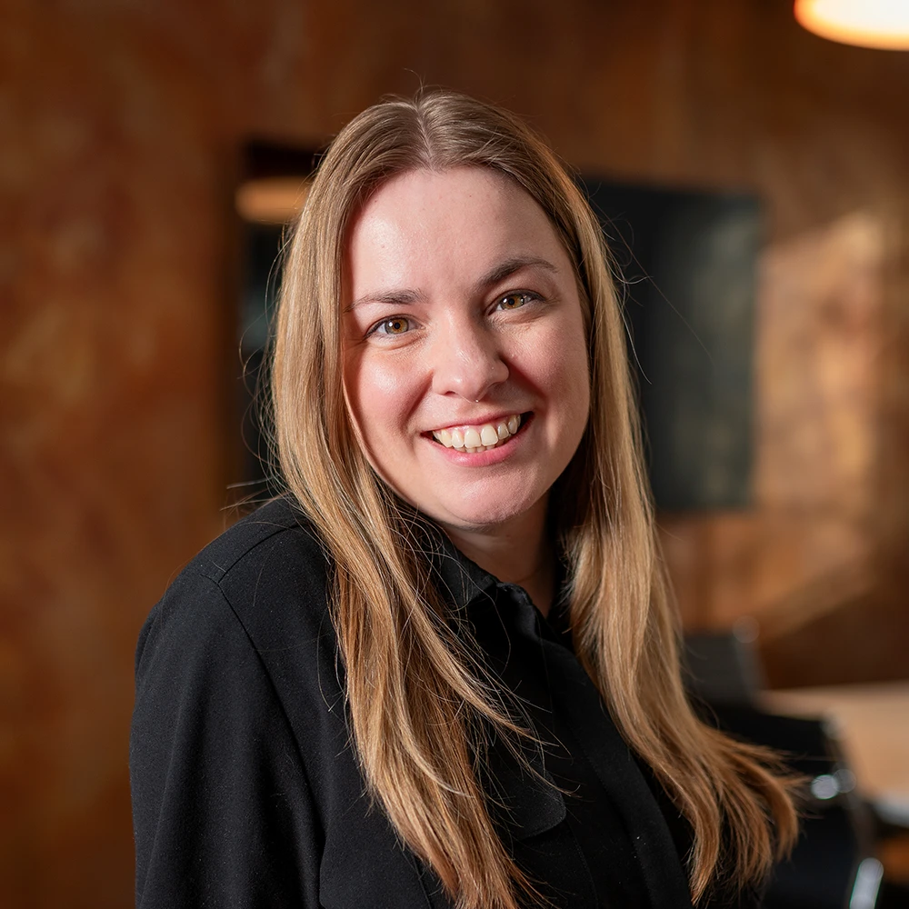 Jessica Vanderlaan, Architectural Associate at GAE Architecture + Design, smiling in a professional setting, emphasizing her commitment to community-focused and sustainable architecture.